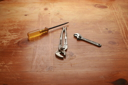 Screwdriver Wrench Plumbers Pliers on wood Table