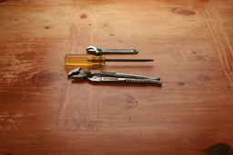 Screwdriver Wrench Plumbers Pliers on wood Table